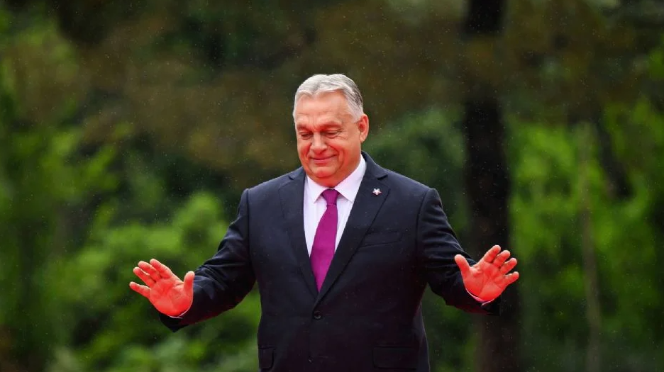 Orbán Viktor miniszterelnök gesztikulál egy zöld háttér előtt.