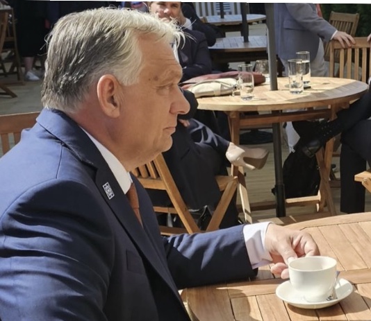 Férfi üzletember ül egy kültéri kávézóban, egy csésze kávét tart a kezében.