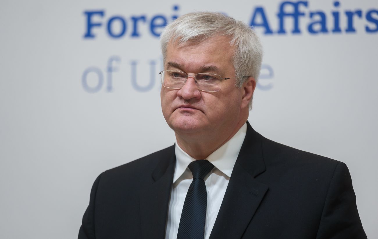 Férfi öltönyben, a Külügyminisztérium felirata a háttérben.
